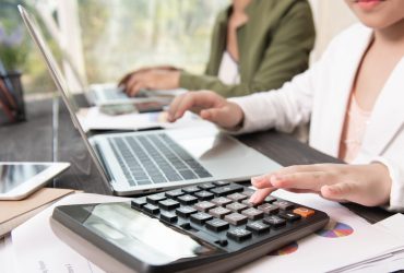 Business woman working teamwork process, Business team using a calculator to calculate the numbers of statistic business profits growth rate on documents graph data, his desk in a office.